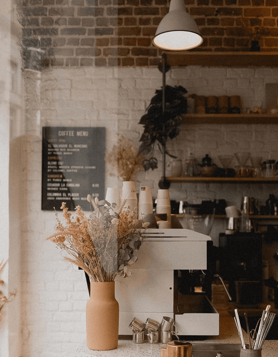 La machine espresso de Kami entre briques, fleurs séchées et carte des cafés du moment