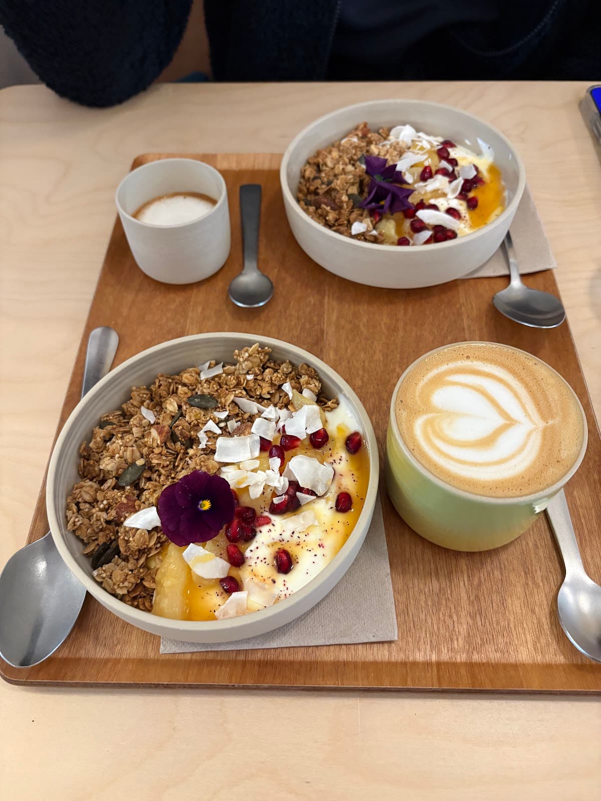 Granola bowls maison — yaourt, grenade, coco et fleur comestible — avec un latte