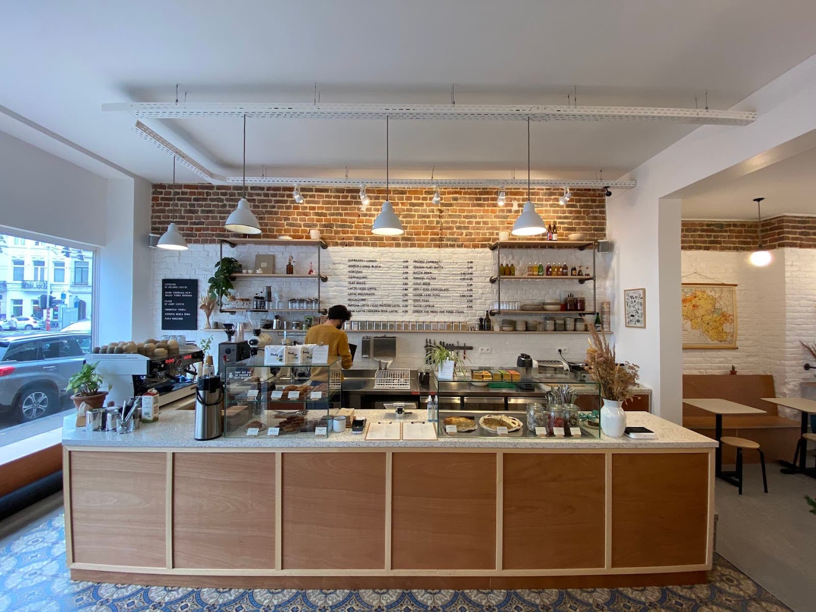 Le comptoir de Kami : bois clair, terrazzo, mur de briques et carte au mur, vitrines de pâtisseries maison